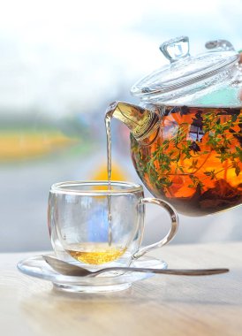 Cam çaydanlıktan cam bir fincana hafif bir arka planda çay dök.