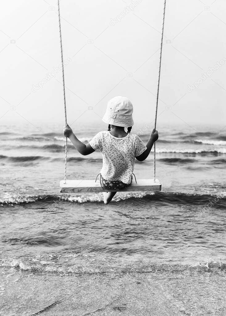 little girl on a swing over the sea
