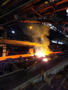 Fabrika atölyesindeki endüstriyel bir fırında yüksek sıcaklıkta çelik sertleşmesi. Metalurji endüstrisi, çelik üretimi, sıcak rulo fabrikası