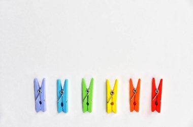 LGBT topluluğu için kartpostal. Beyaz desenli arka planda LGBT renklerinde renkli lothespinler. Fotokopi alanı olan düz konum
