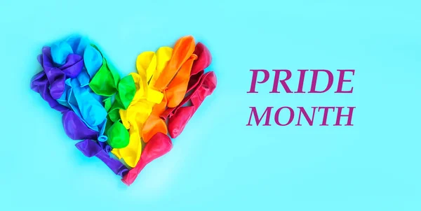 彩虹心是用气球做的心脏 就像蓝色题词背景上的彩虹的旗帜一样 Pride Month 人权和自由的概念与男女同性恋 双性恋和变性者 免版税图库图片