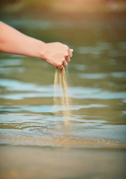 砂が手から水に流れ込んでいます 夏の背景 — ストック写真
