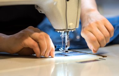 Bir terzinin elleri. Dikiş makinesiyle elbise dikiyor.