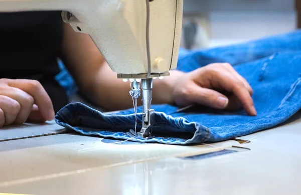 Bir terzinin elleri. Dikiş makinesiyle elbise dikiyor.