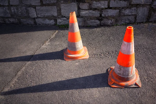Two orange road cones on the gray asphalt
