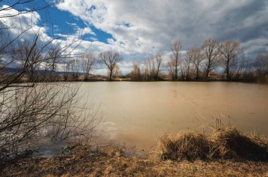 Dramatik gökyüzü altında kirli küçük göl