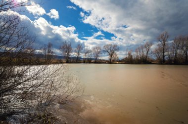 Dramatik gökyüzü altında kirli küçük göl
