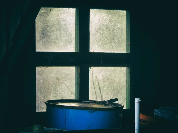 Sala de chatarra con una vieja ventana sucia y un barril azul — Foto de Stock