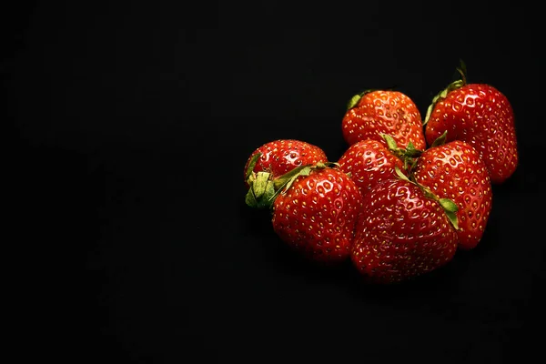 red strawberries on a black background, black isolate, close-up