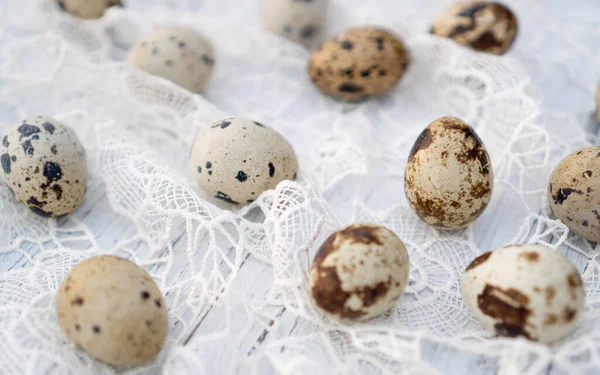 Traditional quail eggs on white table cowered with white crocheted tablecloth. Bright food background.