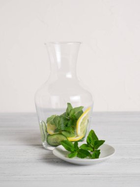 Salatalıklı kavanoz, limon dilimleri ve içinde salatalık suyu tarifi için nane yaprakları. Ev yapımı detoks konsepti. Dikey