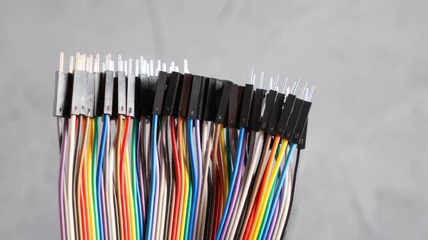 Jumper kabloları bağlantı kablolarının uçları farklı türde. Elektronik devre için renkli kablolar. Betonda gökkuşağı kabloları
