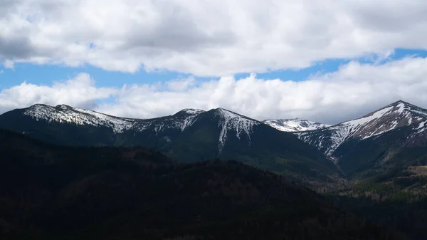 Picos de montaña nevados a la sombra de nubes grises en el cielo. Fondo de contraste. Viajar y relajarse —  Fotos de Stock