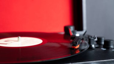 Siyah plaka ve fotokopi alanı üzerinde dönen vinil iğne stili. Kırmızı arkaplanda turntable vinil kayıt oynatıcı