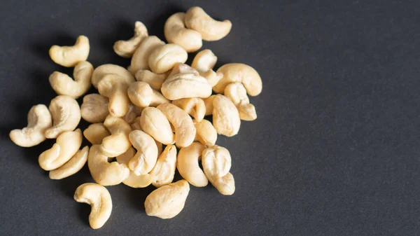 En handfull cashewnötter på svart bakgrund. Del av cashewnötter. Närbild skalade cashewnötter. Ovanifrån med kopieringsutrymme. — Stockfoto