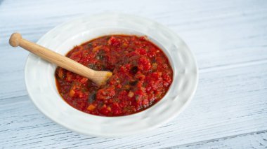 Beyaz ahşap bir masada beyaz bir tabakta, ev yapımı domates sosu maydanozlu domates sosu.