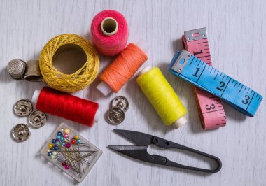 ewing araçları ve aksesuarları dikmek için renkli iplikler, bobinler, makas, düğmeler, iğneler, iğneler, iğne ve terziler beyaz bir arkaplan üzerine dikiş aksesuarları kavramı.
