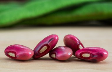 Ahşap bir yüzeyde mor fasulye ve kozaların yaratıcı görüntüsü. Beslenme, sebze, makro