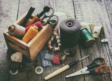 Aksesuar dikme konsepti. Eski ahşap bir yüzeye dikiş aletleri, makaralar, düğmeler, iğneler, iğneler, iğne ve terziler için aksesuarlar dikmek. Retro biçimi.