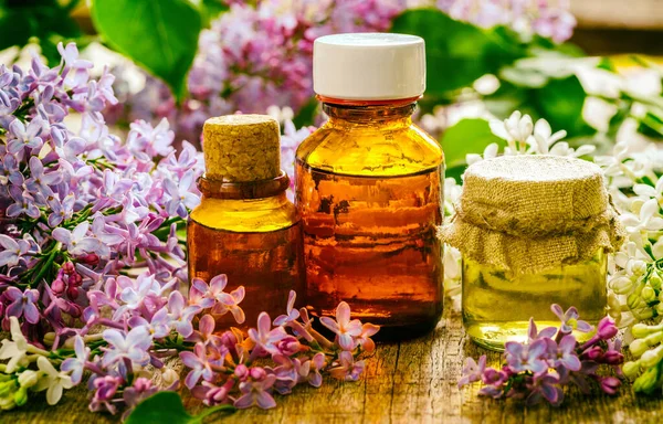 Bottles of natural essential oil from lilac flowers on a wooden surface. Macro Selective focus. Retro tonin