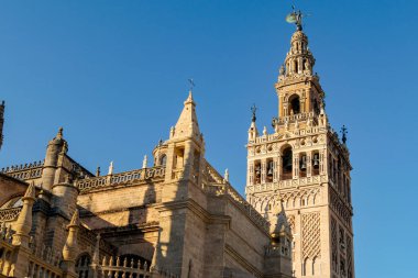 La Giralda Bell Kulesi, güneşli bir öğleden sonra, Sevilla Katedrali 'nin bir tarafından mavi gökyüzü eşliğinde görüldü. Endülüs 'teki UNESCO Dünya Mirası sahası. İspanya.