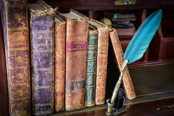 old books on desk and pen writing