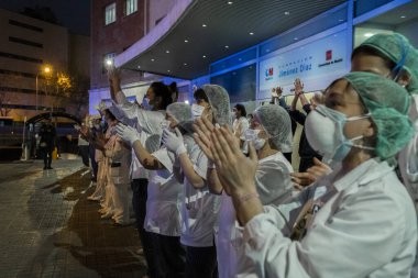 Sağlık personeli, Madrid 'deki Fundacion Jimenez Diaz hastanesinin girişinde Coronavirus' la savaşan insanlara teşekkür etmek için ellerini çırpıyor. Her gün medreseler doktor ve hemşirelere saygılarını sunmak için balkonlarına çıkarlar.