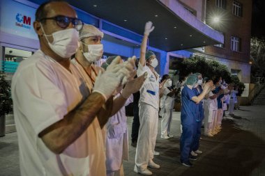 Madrid 'deki Fundacion Jimenez Diaz hastanesinde çalışan bir doktor, Coronavirus ile savaşan insanlara teşekkür etmek için elini sallıyor. Madrilenolar her gün balkonlarına çıkıp onlara saygılarını sunarlar.