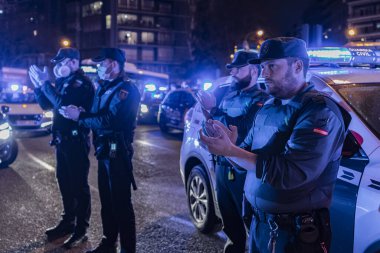 Coronavirus salgınıyla mücadele eden tıbbi personele destek vermek için iki Ulusal Polis ve iki Gardiyan Memuru alkışlıyor. Her gün saat 8 'de polis devriyeleri sağlık çalışanlarına saygılarını sunmak için Fundacion Jimenez Diaz hastanesinin önünde toplanıyor.