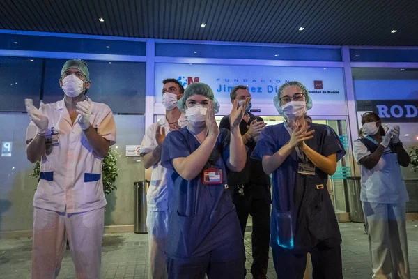 Sağlık personeli, Madrid 'deki Fundacion Jimenez Diaz hastanesinin girişinde Coronavirus' la savaşan insanlara teşekkür etmek için ellerini çırpıyor. Her gün medreseler doktor ve hemşirelere saygılarını sunmak için balkonlarına çıkarlar.