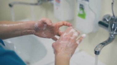 Doktor hastanede tıbbi ameliyattan önce ellerini yoğun bir şekilde sabunla yıkıyor.