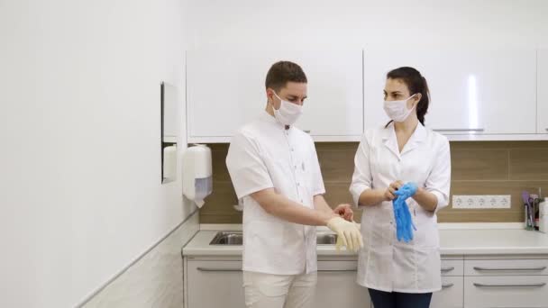 Médicos enmascarados hombres y mujeres se ponen guantes en el hospital en cuarentena durante pandemia — Vídeo de stock