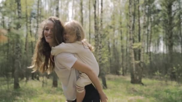 Mladá matka s dlouhými vlasy a její blond dcera hraje v lese, rodinná procházka — Stock video