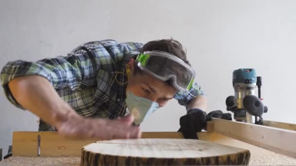 Męski stolarz w masce i rękawiczkach sprawdza odcięte drzewo podczas pracy — Wideo stockowe