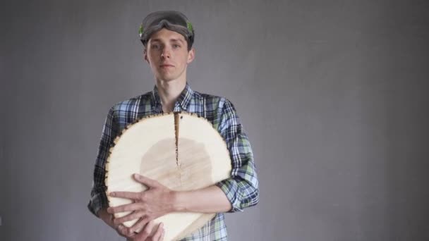 Un menuisier en chemise ceinturée et lunettes, avec un arbre abattu dans ses mains pose pour la caméra — Video