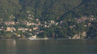 Güneşli bir yaz günü, Como Gölü 'nde, güneşli bir yaz gününde, yeşil bir dağın yamacında, bir İtalyan kasabasının arka planına karşı beyaz bir hidrofolyo gemisi yelken açar.