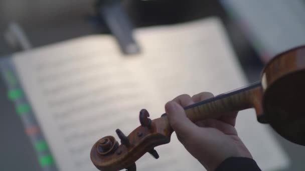 一个男人在音乐笔记本的背景下弹奏小提琴 而笔记本的背景是不对焦的 手指沿着绳子移动 — 图库视频影像