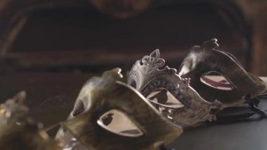 Altın ve gümüş Venedik maskeli ve kayışları olan eski püskü bir masada bir ışık huzmesi içinde bir gölge gibi yatıyorlar. Yaz gününde yumuşak bir hareket.
