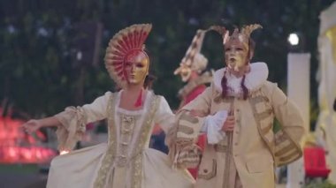 COMO, İTALYA 26 Eylül 2019: Venedik karnaval maskeleri ve klasik kostümlü bir kadın ve bir erkek yeşil ormanın arka planına karşı bir yaz günü zarif bir şekilde kameraya gider.