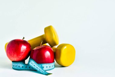 Halterler, kırmızı elmalar ve ölçüm bantları beyaz arka planda izole edilmiş. mesaj için yer. Gıda ve kilo kaybı kavramı.