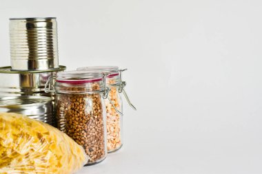 İzolasyon ve karantina süresince ev teslimatıyla ilgili krizde olan erzaklar. Kavanozda karabuğday, konserve yiyecek, makarna, beyaz arka planda tuvalet kağıdı. Yakın çekim görüntüsü. Coronavirüs
