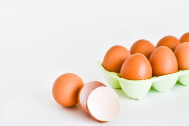 Beyaz bir tabakta çiğ tavuk yumurtası ve boş bir kırmızı ile ayrı ayrı yumurtalar. Metin için yer.