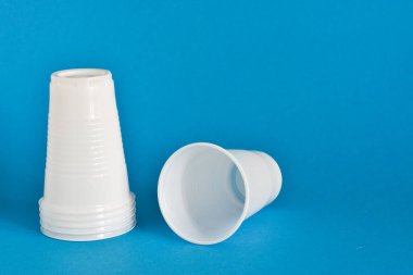 Arka planda tek kullanımlık plastik bardaklar. Çöp öğütücüye bakıyorum. Tekrar kullan, güvenli gezegen. Metin için yer.