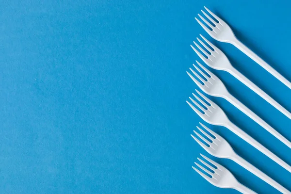 Arka planda plastik tek kullanımlık çatallar. Çevreye önem vermek. İmha sorunu. Yeniden kullanım, güvenli gezegen, çevre kavramı.