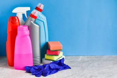 Temizlik ve düzenleme için hazır, aksesuarlar mutfak masasında, mavi arka planda. Metin için yer.