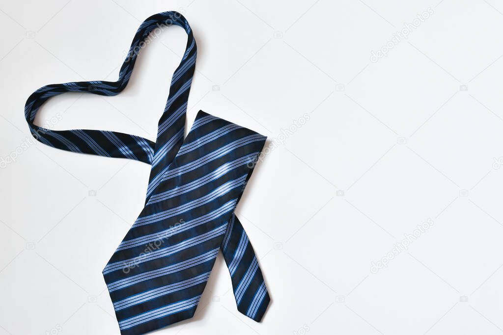 Blue tie laid out in the form of a heart on a fir-tree background. Father and business day concept