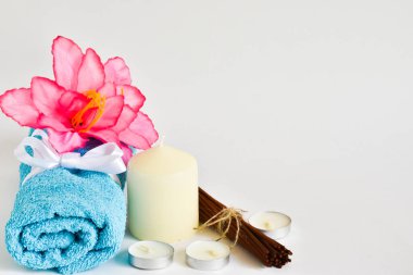 Mum, havlu, banyo tuzu ve pembe çiçekli spa seti, beyaz arka planda tütsü çubukları, metin için yer