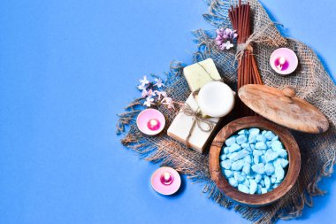 Spa natürmort. Banyo tuzu, sabun, tütsü çubukları ve deniz kabuğunda kokulu mumlar, mavi bir arka planda. Metin için yer