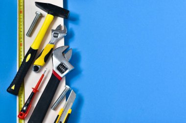 Tamir için inşaat aletleri, inşaat alanları ahşap bir tahtanın üzerinde, mavi bir arka planda. Mesaj için yer. İnşaat ve onarım kavramı.