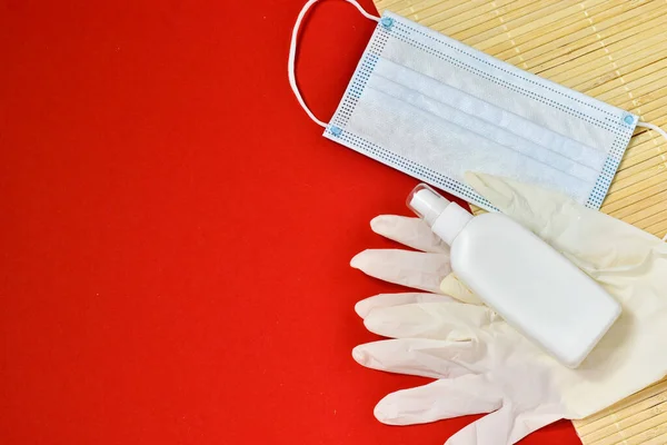 Medical gloves, medical mask and hand antiseptic, for safety against viruses on a red background. Health concept. coronavirus, covid 19. Place for text.